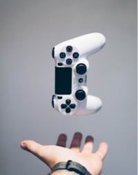 A person holding a game controller with a glowing screen in the background